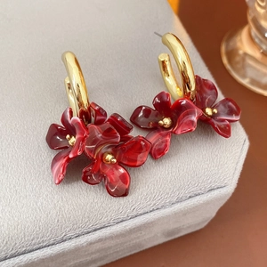 Macro view of C-shaped earrings with red gradient floral petals and gold rings