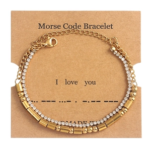 Detailed view of Morse Code double-layer gold bracelet with crystals on display card