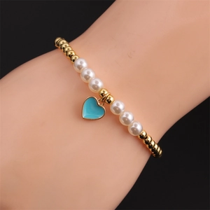 Close-up of pearl and gold bead stretch bracelet with a blue heart-shaped oil pendant
