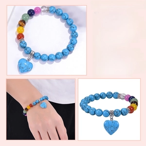 Detail of 8mm pink quartz and chakra stone bracelet with heart pendant on a model's wrist