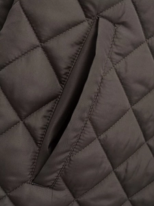 Detail of diamond-quilted pattern and side pocket on dark loose winter coat