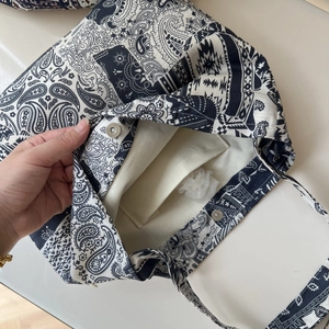 Close-up of bohemian linen tote featuring paisley print, magnetic closure, and inner pocket