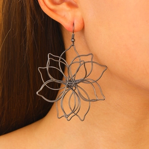 Close-up of artistic black hollow floral earring with intricate metal wire petals on model