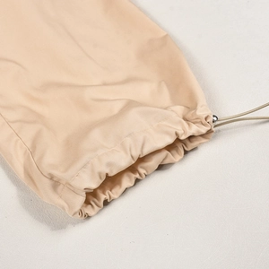 Detailed macro view of adjustable drawstring hem with toggle on beige woven cargo pants