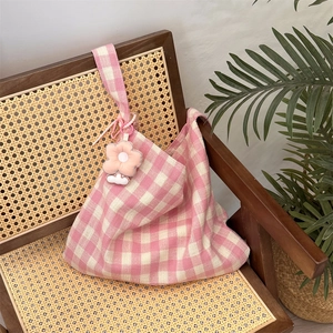 Close-up of pink gingham canvas bag texture with cute floral plush charm on wooden chair