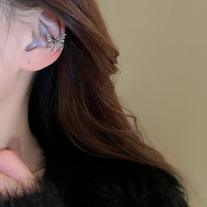Macro shot of silver butterfly ear cuff without piercing on model's ear cartilage