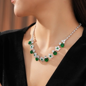 Detailed close-up of a zircon flower necklace with green emerald-cut stones on a model