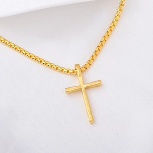 Detailed macro view of a gold-toned cross pendant with a classic box chain