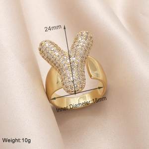 Detailed view of gold letter Y ring with zircon inlay on beige silk including dimensions