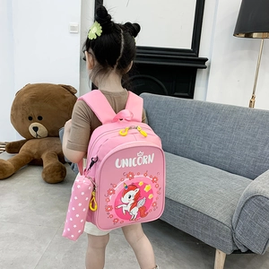 Pink unicorn kids backpack with matching pencil case shown in a cozy home setting