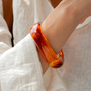 Close-up of vintage amber acrylic bangle with elegant resin swirl patterns on wrist