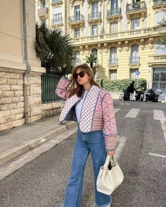 Outdoor shot of a reversible quilted jacket featuring pink and blue floral patchwork design