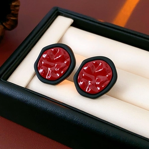 Détail macro de boucles d'oreilles hexagonales irrégulières avec texture rouge foncé