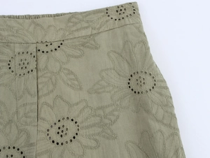 Detail of olive green embroidered fabric with eyelet patterns and elastic waistband