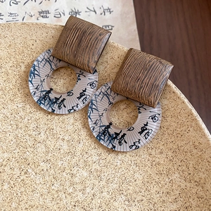 Close-up of vintage resin earrings with geometric wood texture and calligraphy details