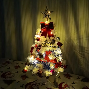 Detail of decorated mini Christmas tree with festive ornaments and warm LED lights