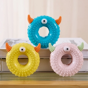 Three colorful monster-shaped squeaky donut pet toys with texture on white book