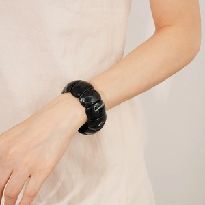 Detail of chunky black acrylic geometric bracelet with white marble texture on wrist