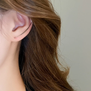 Nahaufnahme des minimalistischen silbernen Ohrhakens am Ohr mit glattem Metall-Finish