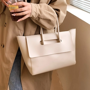 Minimalist beige leather tote bag for women shown with model in a stylish indoor setting