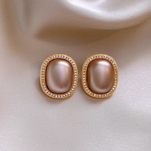 Detailed close-up of vintage gold oval pearl earrings with micro-inlaid zircon on beige silk