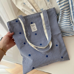 Close-up of blue and white checkered canvas tote bag with delicate embroidery details