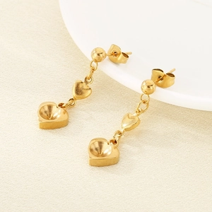Detail of golden stainless steel heart-shaped charm earrings with gemstone base settings