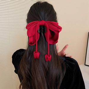 Pince à cheveux nœud rouge avec glands tulipes sur de longs cheveux bruns ondulés