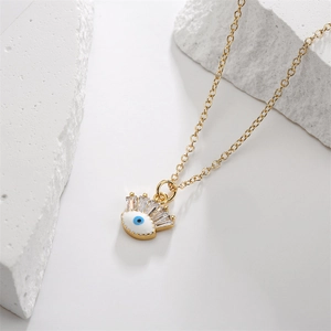 Macro detail of gold evil eye necklace with blue zircon and white enamel pendant