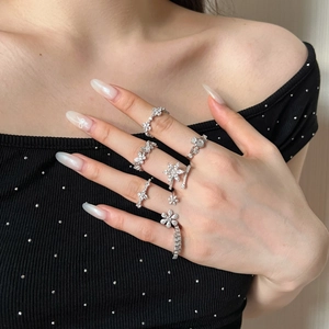Detailed view of model wearing multiple S925 silver flower and star rings with zircons