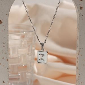 Macro shot of silver letter K pendant necklace on a minimalist decorative arch background