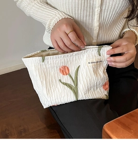 Close-up of white canvas makeup bag with pink tulip embroidery and zipper closure