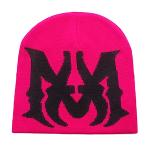 Close-up of bright pink knitted beanie featuring black MM letter jacquard patterns