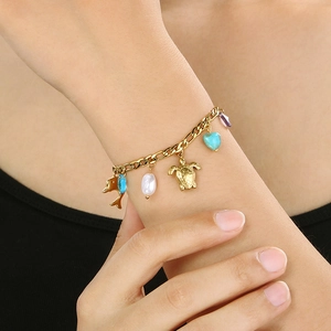 Détail d'un bracelet doré thème océan avec breloques tortue, dauphin, cœur et perles