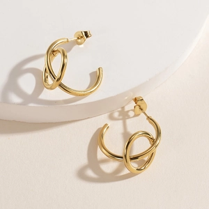 Close-up of 14K gold plated C-shaped earrings with unique twist knot design on white prop