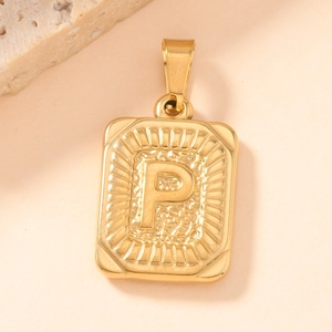 Macro detail of square gold stainless steel pendant with letter P and sunburst texture