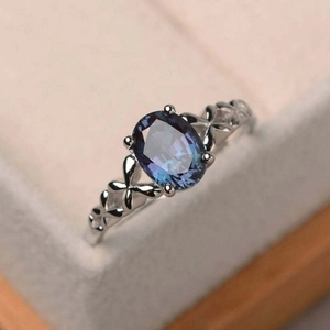 Macro shot of oval-cut blue purple gemstone on rose gold floral hollow band ring