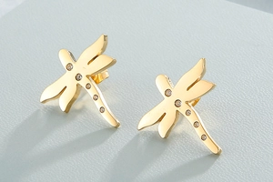 Macro detail of golden dragonfly stud earrings featuring sparkling white rhinestones