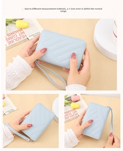 Close-up of light blue quilted short wallet featuring a matching wrist strap and zipper