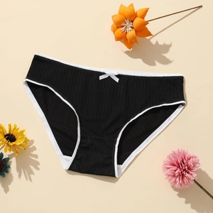 Black ribbed polyester panties with white lace trim and a bow on beige background