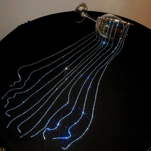 Detailed view of silver hairband featuring long dangling blue and white rhinestone chains