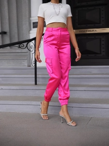 Bright pink satin cargo pants with side pockets and cinched cuffs in street style