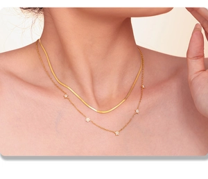 Close-up of a double-layered gold necklace with star charms and a sleek snake chain