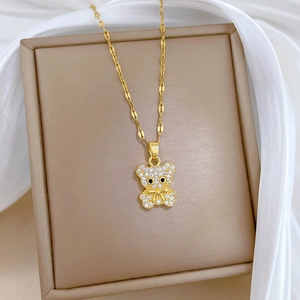 Golden titanium steel teddy bear necklace with zircon inlays on a beige jewelry box
