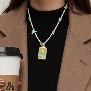Bohemian gold sun pendant necklace with turquoise beads worn on a casual outfit