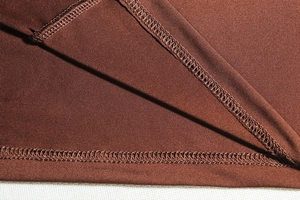 Détail de la couture à double aiguille et de la texture du tissu d'une robe marron foncé