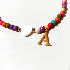 Colorful beaded necklace with white heart charm and gold letter A pendant for women