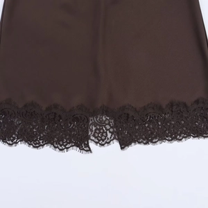 Detail van de donkerbruine satijnen zoom met elegante bloemenkant voor deze luxe rok