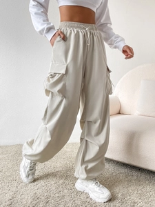 Detail view of baggy cargo pants in off-white featuring elastic waist and side pockets
