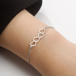 Minimalist silver stainless steel bracelet featuring four hollow heart-shaped pendants